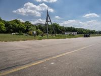 a parking lot with a traffic light and power lines near a wooded area surrounded by trees