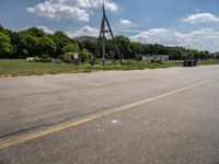 a parking lot with a traffic light and power lines near a wooded area surrounded by trees