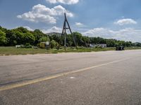 a parking lot with a traffic light and power lines near a wooded area surrounded by trees