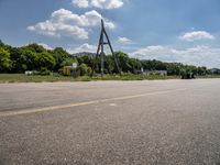 a parking lot with a traffic light and power lines near a wooded area surrounded by trees