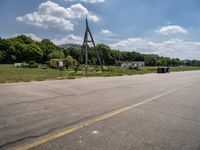 a parking lot with a traffic light and power lines near a wooded area surrounded by trees