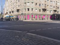 there is a pink building on the corner of this street, with a bicycle rack in the middle