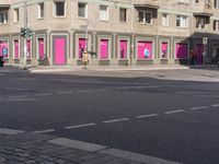 there is a pink building on the corner of this street, with a bicycle rack in the middle