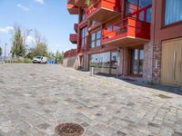 a paved sidewalk lined with red building buildings and a manhole in the middle of it