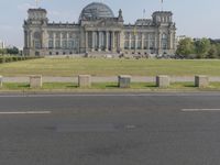 a view of the reich chancel with a fence and people walking outside of it and a large building in the background