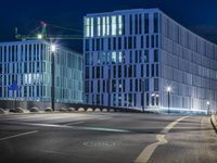 large building on the street with lights in front and other buildings nearby at night with no one moving