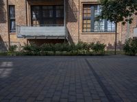 an outside photo of a brick building and a bench in the middle of it and a black car sitting parked by