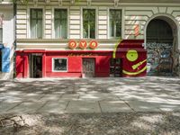 a restaurant in the middle of a narrow city street with graffiti on the wall and the sidewalk outside the building