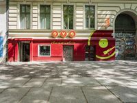 a restaurant in the middle of a narrow city street with graffiti on the wall and the sidewalk outside the building