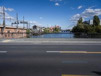 a road and bridge with a river in the distance and buildings across from it in front and on either side