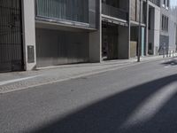 a person riding a bike on the road outside of building in sunshine light and shadow