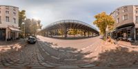 a 360 - fish eye photo of the road next to buildings and bikes in a city