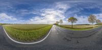 two roads stretching in the middle of a grassy field with a sky background and clouds