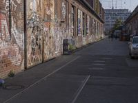 a brick building with lots of graffiti on it and cars parked near the building with windows