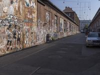 a brick building with lots of graffiti on it and cars parked near the building with windows