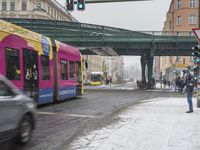 a bus driving under an overpass on the street in the city in snow weather