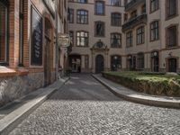 an empty cobblestone street is shown in the early evening sunshine in this urban setting