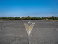 a yellow arrow pointing up to an upward point on a runway at an airfield with houses in the background