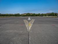 a yellow arrow pointing up to an upward point on a runway at an airfield with houses in the background