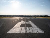 the sun is setting on an airport runway with the runway and airplane taxiway marked