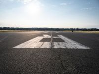 the sun is setting on an airport runway with the runway and airplane taxiway marked