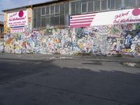 a brick wall covered in graffiti on the street corner of a building with a few signs