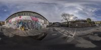 an outdoor skateboard park with a building covered in graffiti and graffiti on the wall