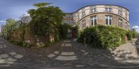 the street looks like an oval shape with ivy growing around it and in this one there a very old house