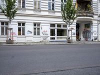 the empty street outside of an older building with graffiti on it, with stairs leading to each side and two parked bicycles on either side