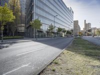 empty street with many tall buildings and trees in front of the street and on opposite sides of the road