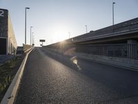 the sun is setting behind the roadway and cars are on the road at dusk or night