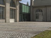 a courtyard with grass and windows is shown here, outside a building, with a paved walkway and sidewalk