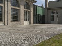 a courtyard with grass and windows is shown here, outside a building, with a paved walkway and sidewalk