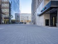 the empty street has cars parked in front of it and tall buildings in the background