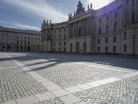 empty cobblestone walkway outside a large castle like building in europe by the sea