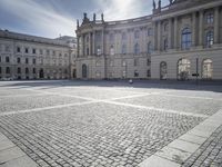 empty cobblestone walkway outside a large castle like building in europe by the sea