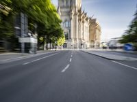 a city street with trees on both sides and the building behind it, blurred with light