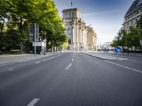 a city street with trees on both sides and the building behind it, blurred with light