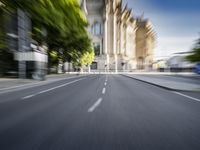 a city street with trees on both sides and the building behind it, blurred with light