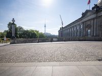 a large stone floor that is in front of a building with large columns and a statue on the sidewalk