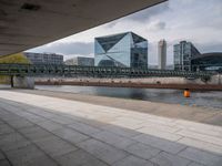 a train sitting next to a long building in a big city area with tall buildings