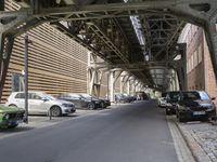 there is a car parked under a bridge in this photo of an alley way in the city