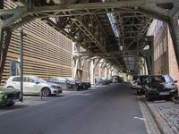 there is a car parked under a bridge in this photo of an alley way in the city