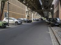 there is a car parked under a bridge in this photo of an alley way in the city