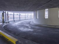 a car parked inside of a parking garage underpasss with a bench near the road