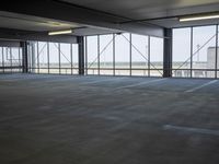 an empty parking lot with a lot of parking spaces on the floor, near large windows