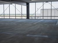 an empty parking lot with a lot of parking spaces on the floor, near large windows