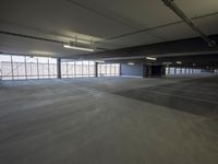 an empty parking lot with a lot of parking spaces on the floor, near large windows
