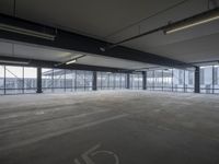 an empty parking lot with a lot of parking spaces on the floor, near large windows