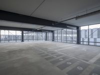 an empty parking lot with a lot of parking spaces on the floor, near large windows